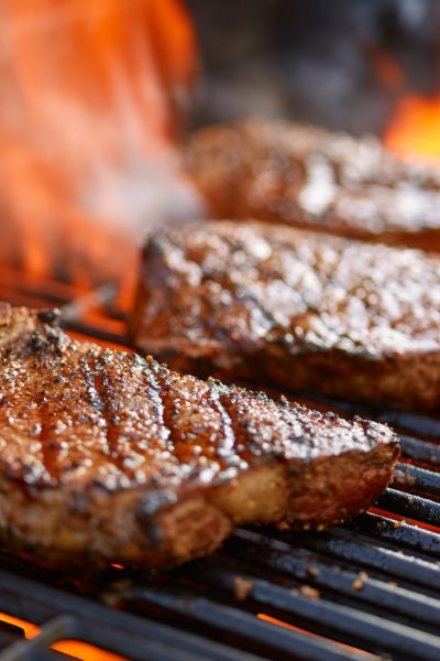 grilling steaks on flaming grill and shot with selective focus